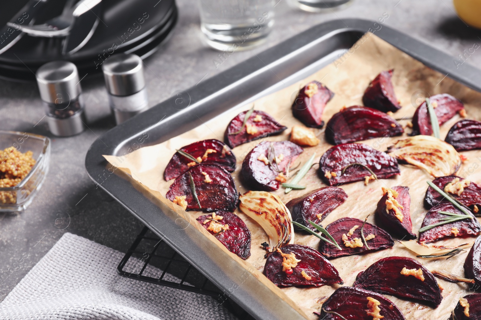 Photo of Baking tray with roasted beetroot slices on grey table, closeup