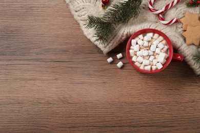 Photo of Flat lay composition with marshmallows, hot drink and plaid on wooden table. Space for text