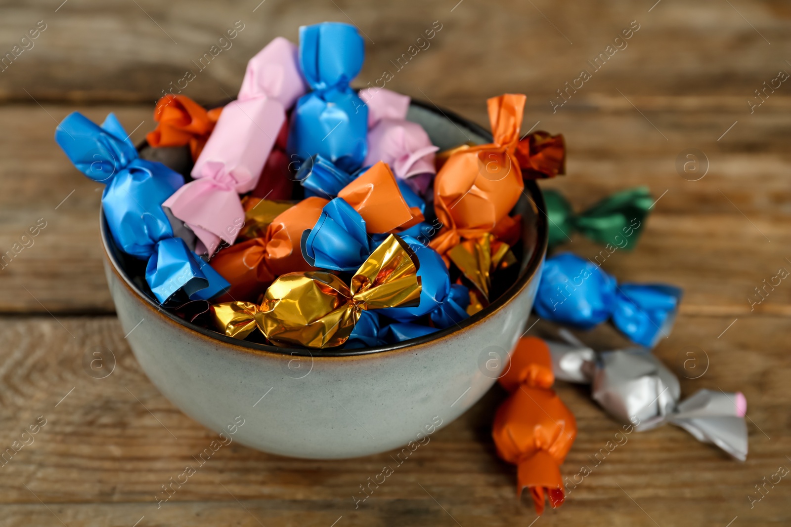 Photo of Candies in colorful wrappers on wooden table, closeup