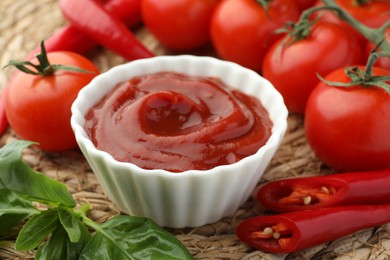 Bowl of tasty ketchup and ingredients on wicker mat, closeup