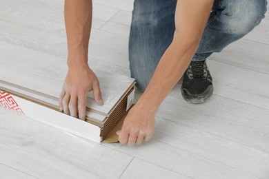 Photo of Professional worker installing new laminate flooring, closeup