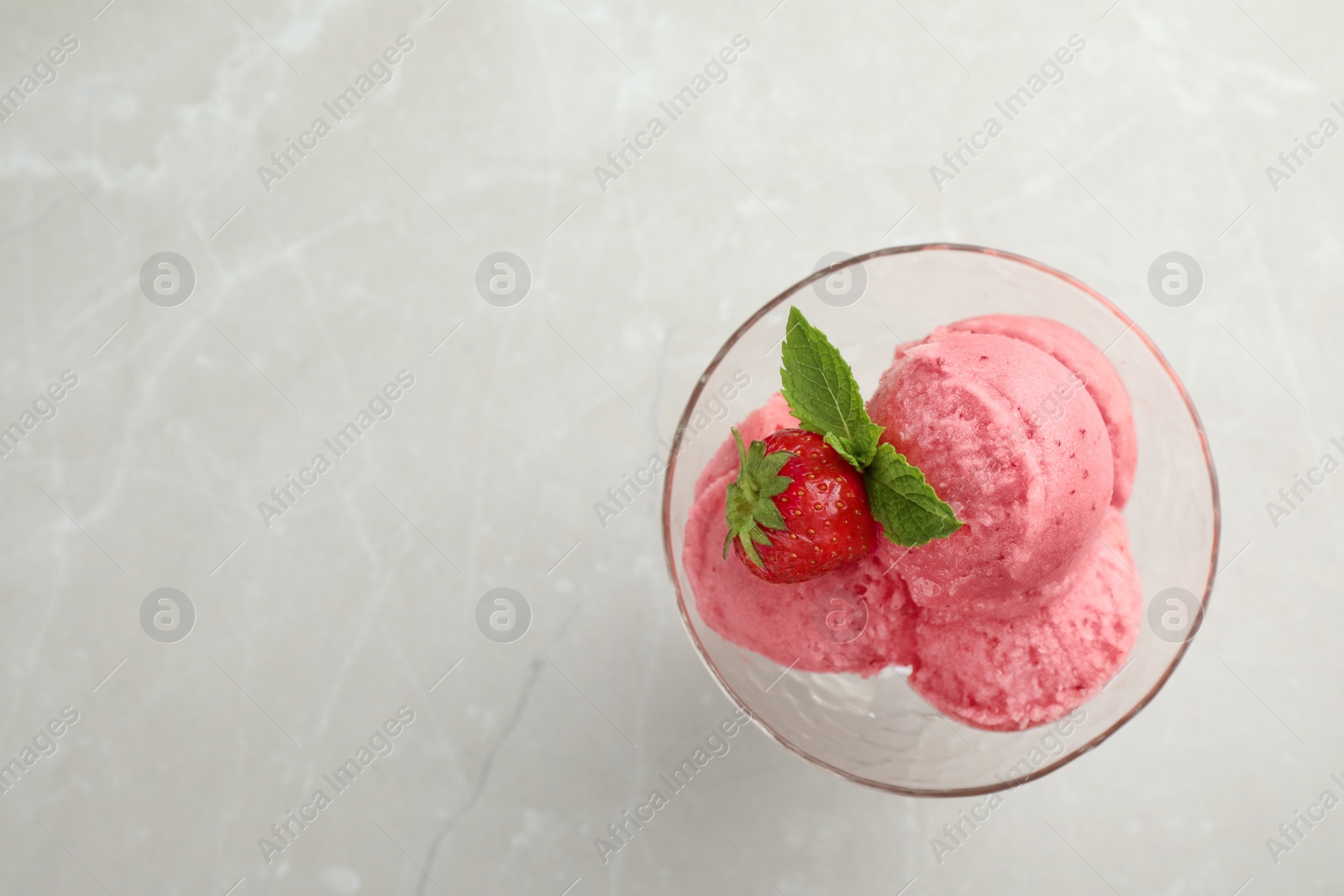 Photo of Delicious strawberry ice cream in dessert bowl on grey marble table, top view. Space for text