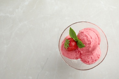 Delicious strawberry ice cream in dessert bowl on grey marble table, top view. Space for text