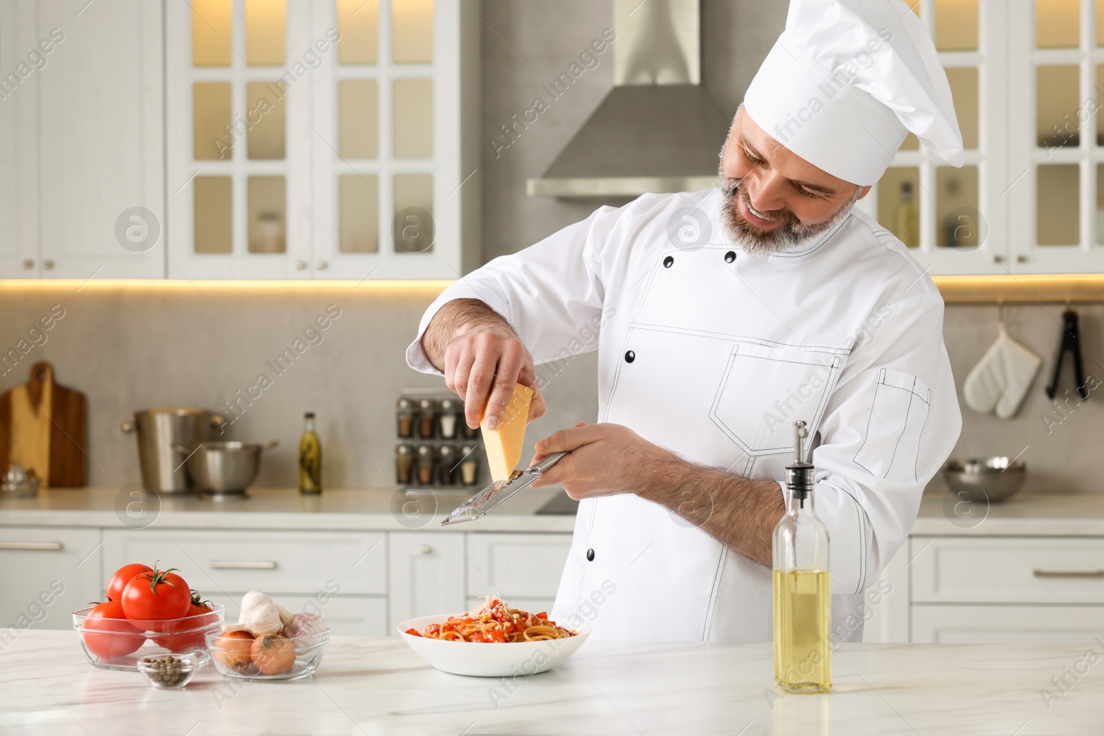 Photo of Professional chef grating cheese into delicious dish at white marble table indoors. Space for text