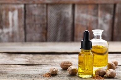 Photo of Bottles of nutmeg oil, nuts and powder on wooden table. Space for text