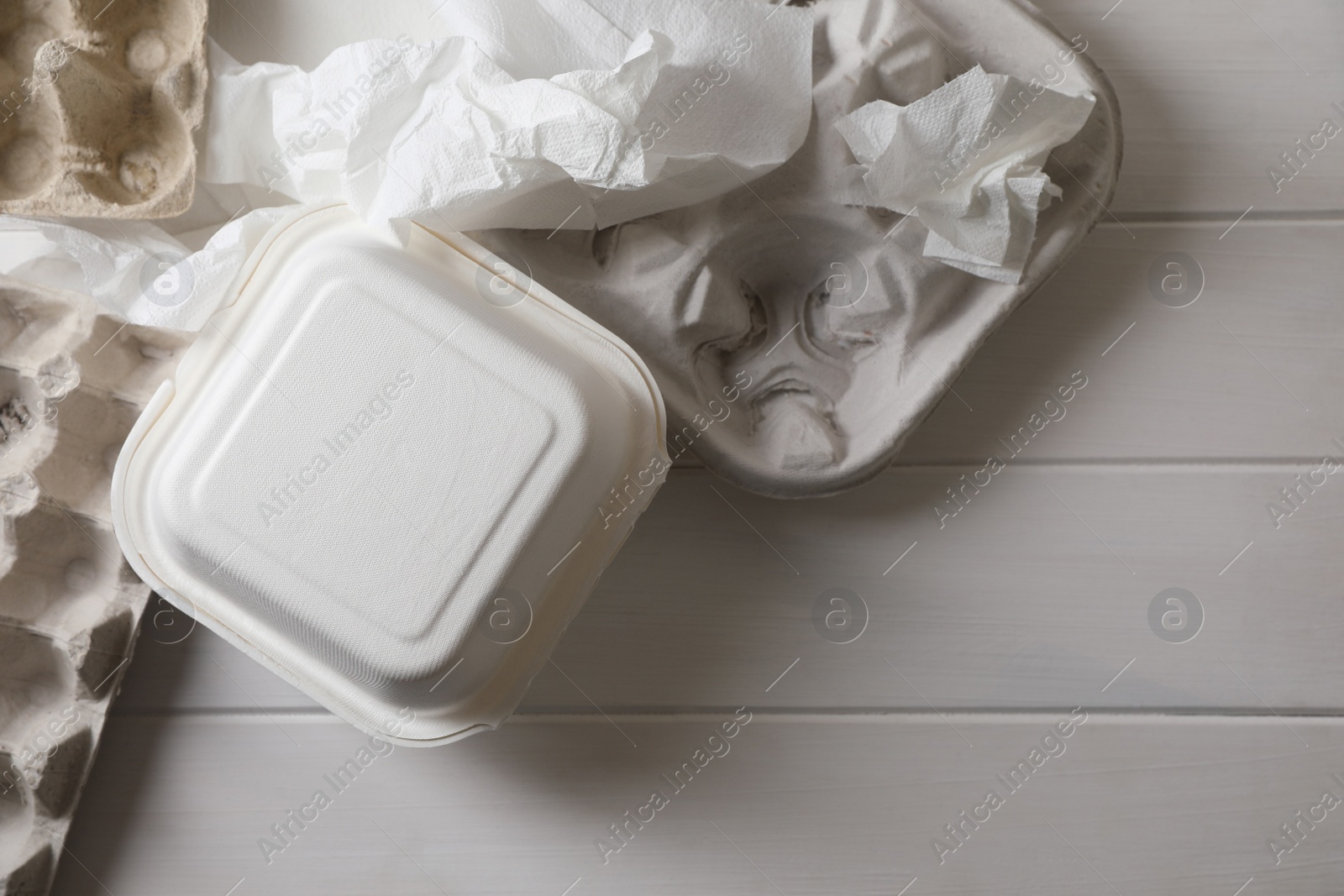 Photo of Heap of waste paper on white wooden table, flat lay. Space for text