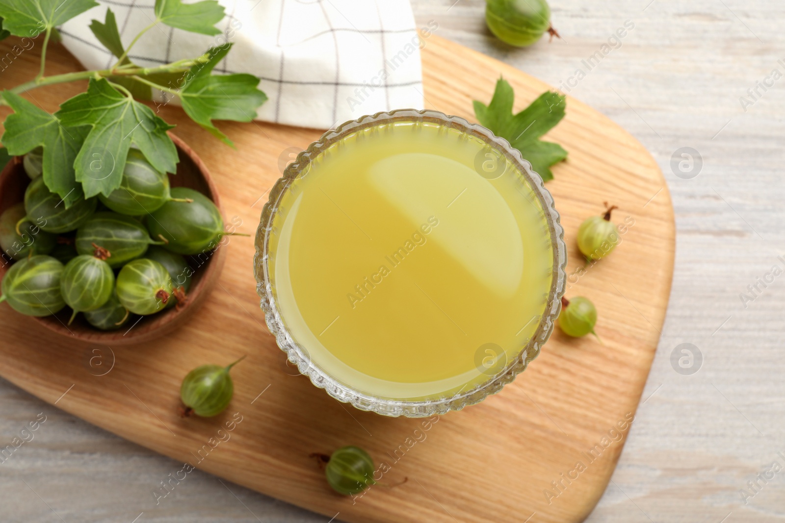 Photo of Tasty gooseberry juice and fresh berries on light wooden table, flat lay