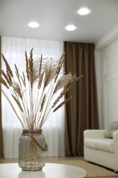 Photo of Fluffy reed plumes on white table in living room interior