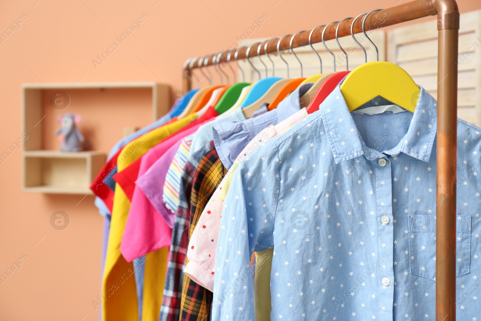 Photo of Different child's clothes hanging on rack indoors, closeup