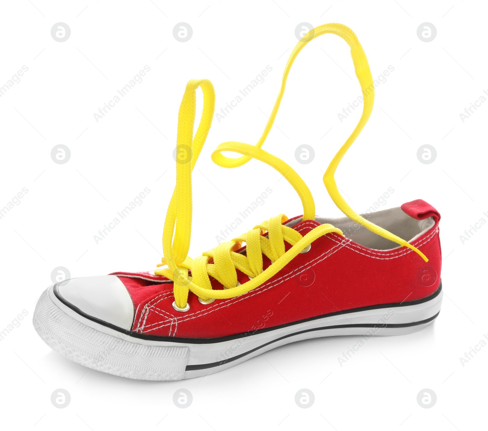 Photo of Stylish red canvas shoe with yellow laces on white background