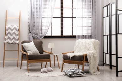 Cozy interior with armchairs, pillows and plaid near window