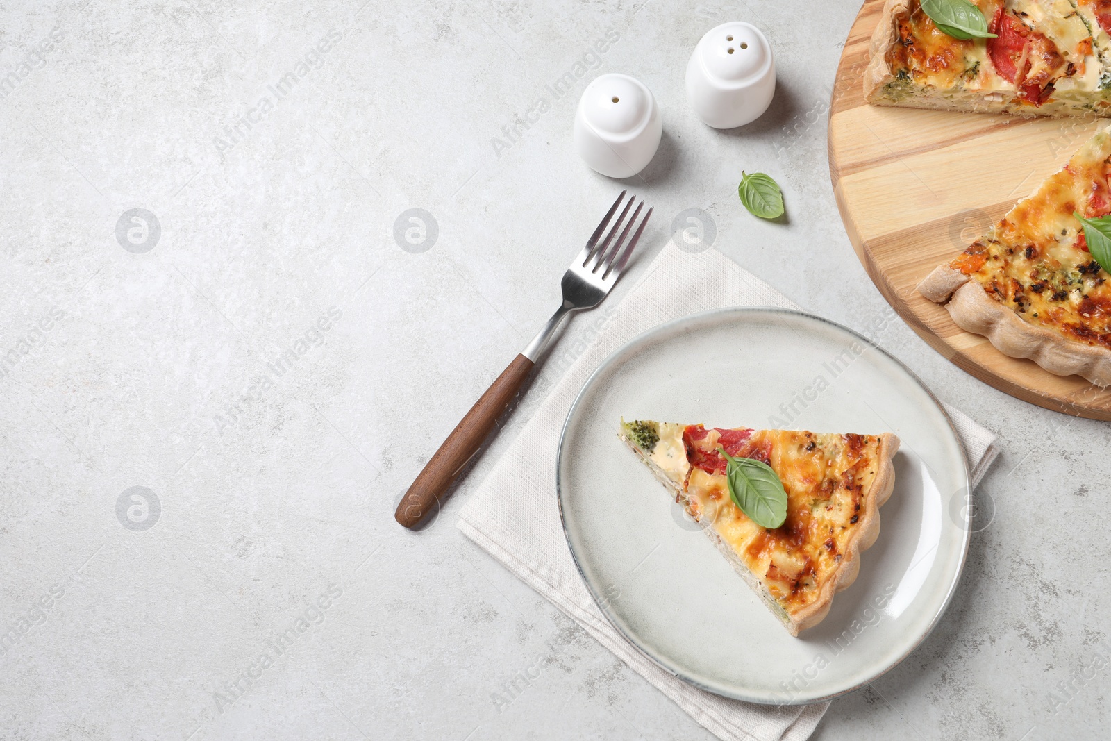 Photo of Tasty quiche with tomatoes, basil and cheese served on light textured table, flat lay. Space for text