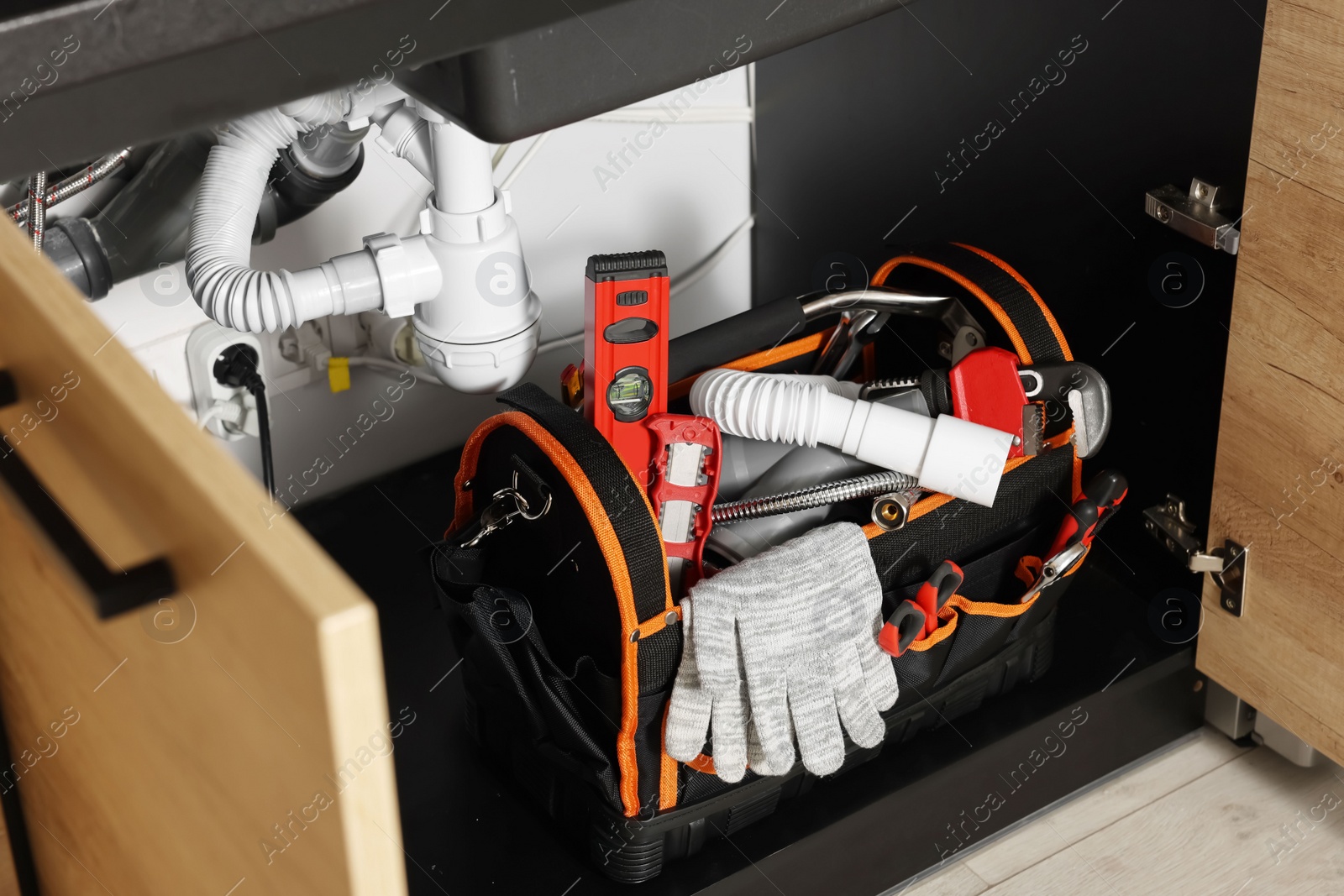 Photo of Plumber's tool bag on floor under kitchen sink