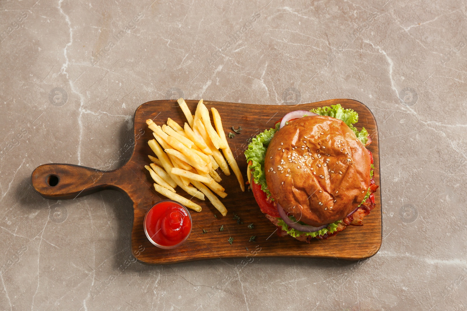 Photo of Wooden board with delicious burger, french fries and sauce on grey background, top view