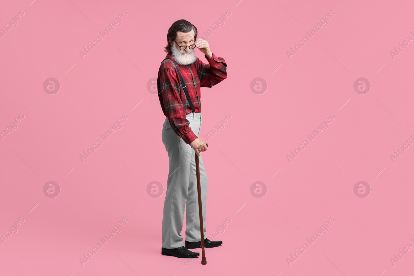 Photo of Senior man with walking cane on pink background