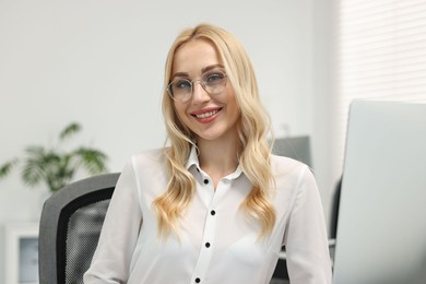 Photo of Portrait of happy secretary in glasses in office