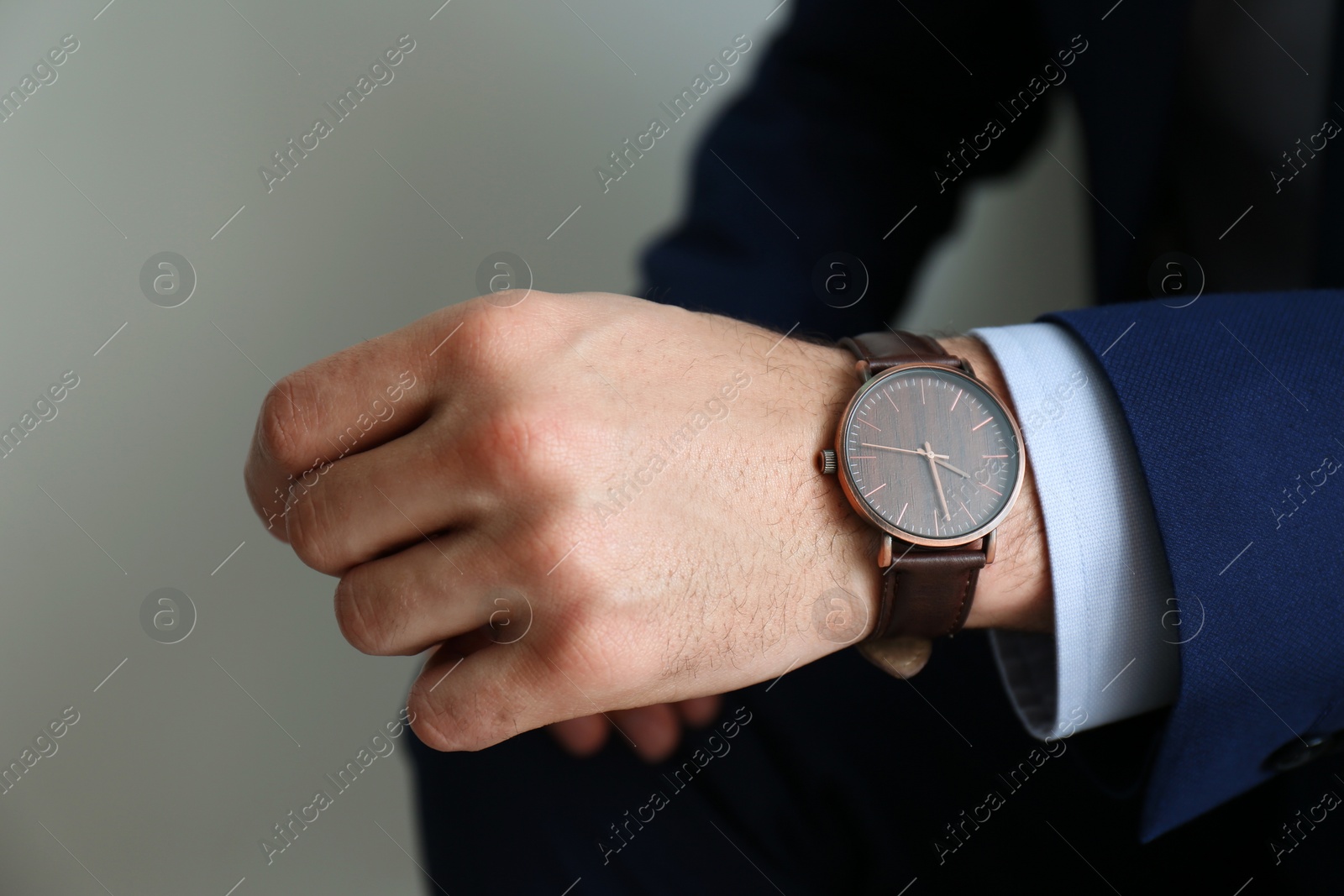 Photo of Businessman with luxury wrist watch on grey background, closeup