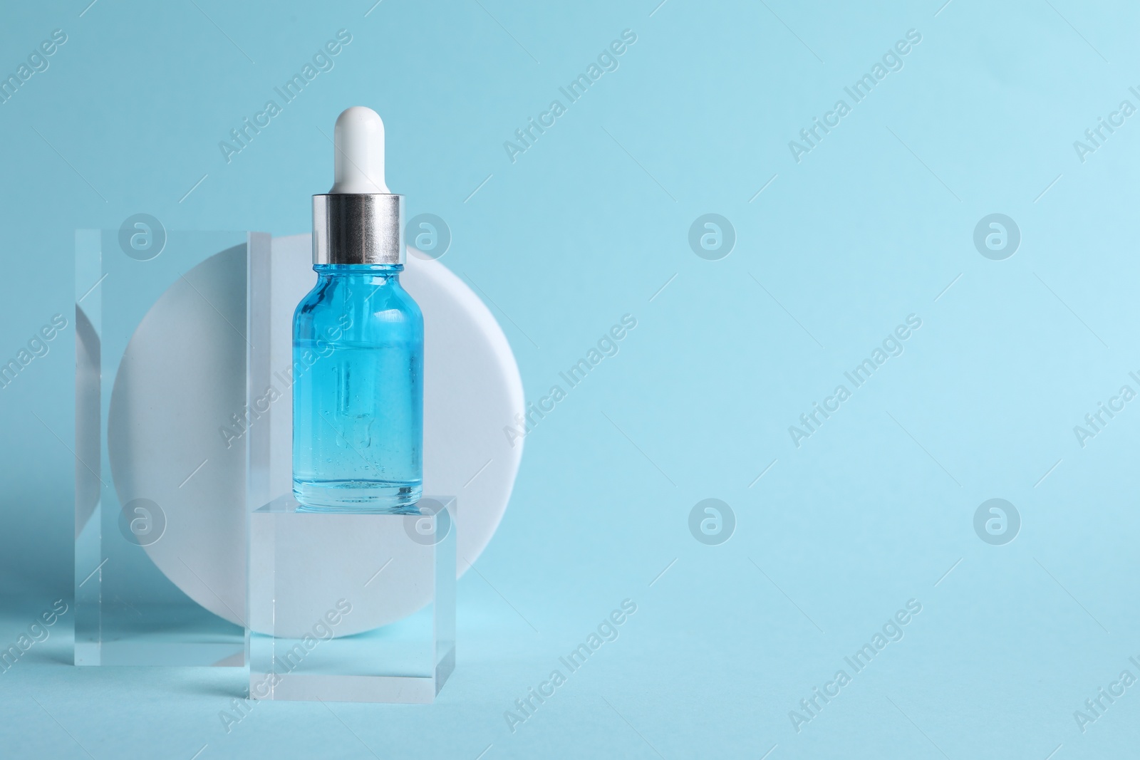 Photo of Stylish presentation of cosmetic serum on light blue background, space for text