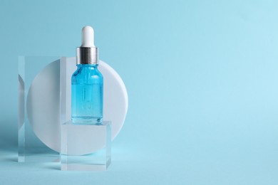 Photo of Stylish presentation of cosmetic serum on light blue background, space for text