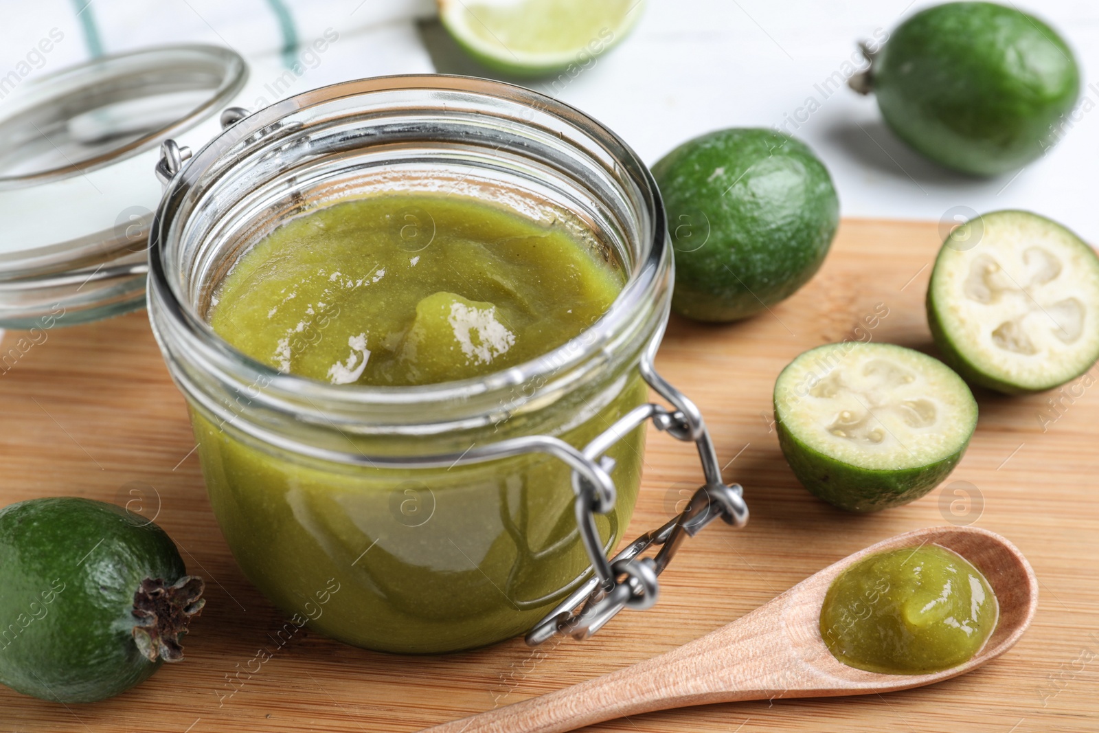 Photo of Feijoa jam and fresh fruits on wooden board, closeup