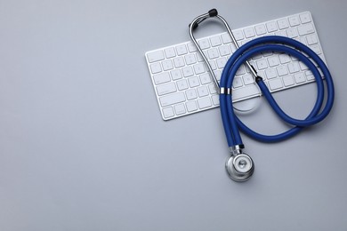 Photo of Keyboard and stethoscope on white background, flat lay. Space for text