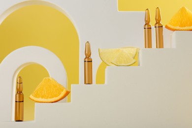 Photo of Stylish presentation of skincare ampoules with vitamin C and citrus slices on decorative stairs against yellow background, closeup