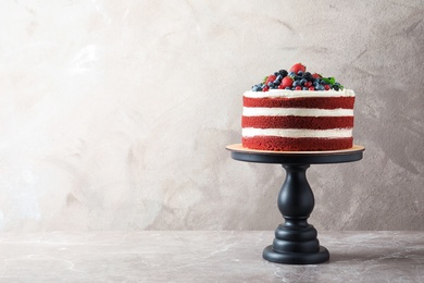 Photo of Stand with delicious homemade red velvet cake and space for text on color background