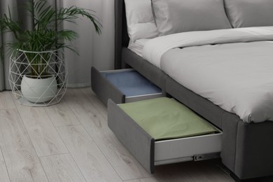 Storage drawers with bedding under modern bed in room