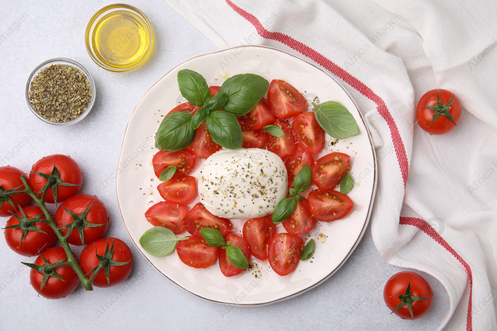 Photo of Tasty salad Caprese with mozarella, tomatoes, basil and other ingredients on light table, flat lay