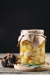 Photo of Garlic with honey in glass jar and fermented black garlic on wooden table