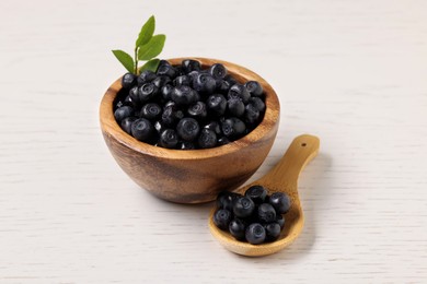 Ripe bilberries and sprig on white wooden table