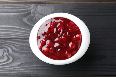 Photo of Fresh cranberry sauce in bowl on black wooden table, top view