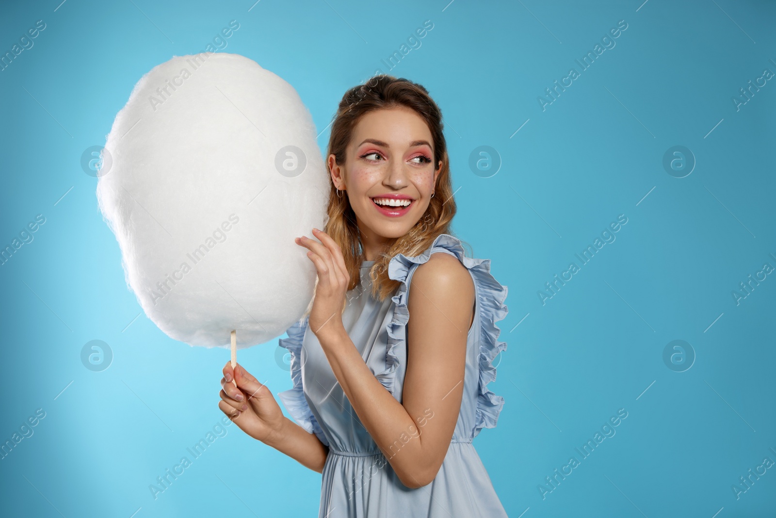 Photo of Portrait of pretty young woman with cotton candy on blue background