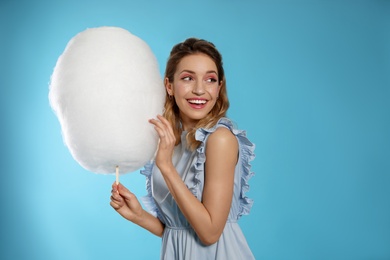 Portrait of pretty young woman with cotton candy on blue background