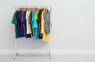 Photo of Rack with stylish clothes in room. Space for text