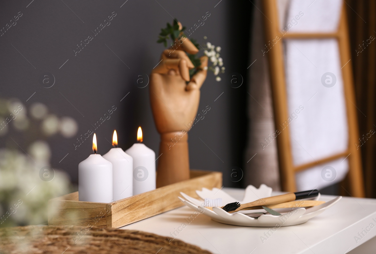 Photo of White table with burning candles and toothbrushes in bathroom