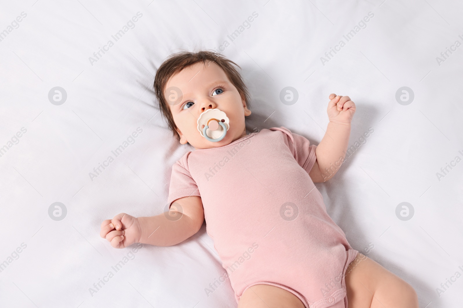 Photo of Cute little baby on cosy bed, top view