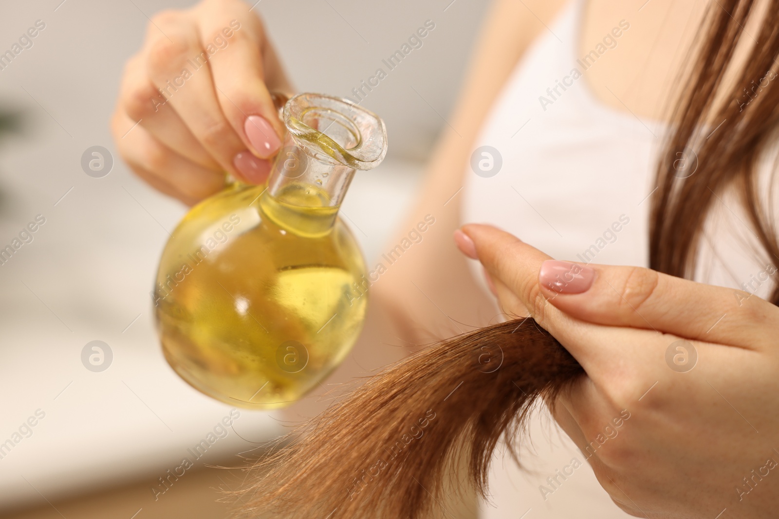 Photo of Woman applying oil hair mask at home, closeup