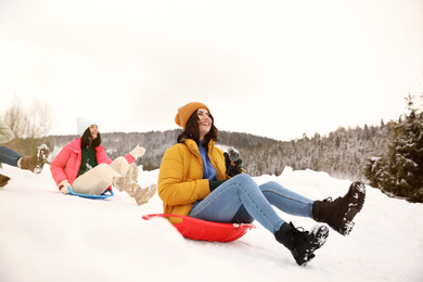 Group of friends having fun and sledding on snow. Winter vacation