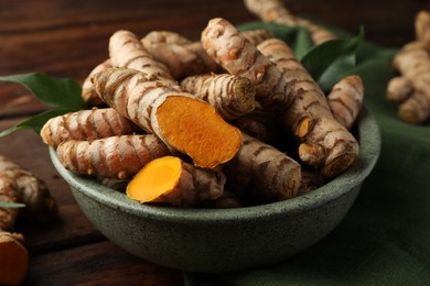 Photo of Fresh turmeric roots on wooden table, closeup