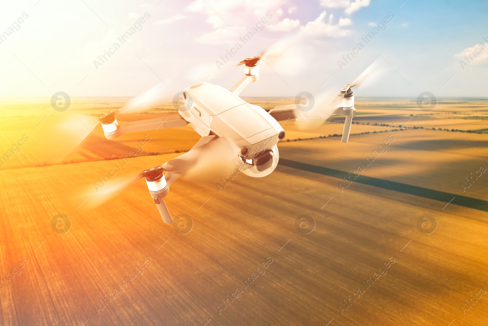 Image of Modern drone flying over field on sunny day. Aerial survey