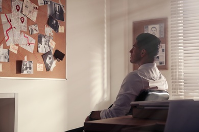 Detective looking at evidence board in office