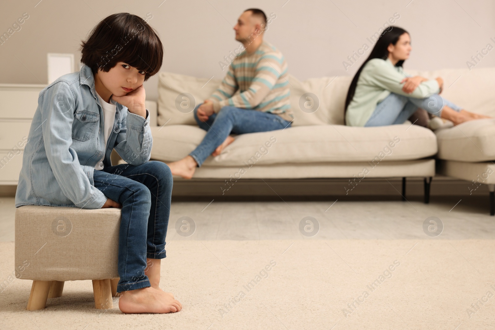 Photo of Sad couple with relationship problems at home, focus on their upset child