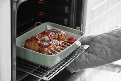 Photo of Chef taking delicious roasted ribs out of oven, closeup