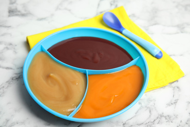 Photo of Healthy baby food and spoon on white marble table, closeup