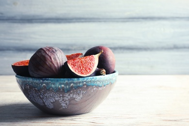 Bowl with fresh ripe figs on wooden background. Tropical fruit