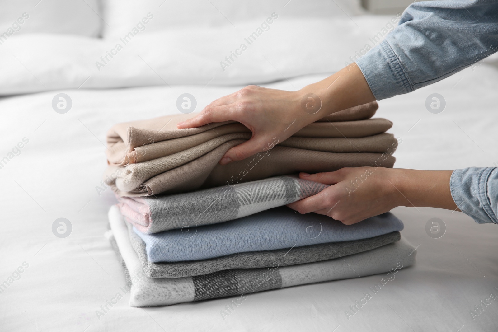 Photo of Woman with folded cashmere clothes on bed, closeup