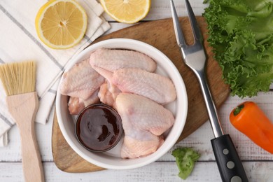 Photo of Flat lay composition with marinade, raw chicken wings and other products on rustic wooden table