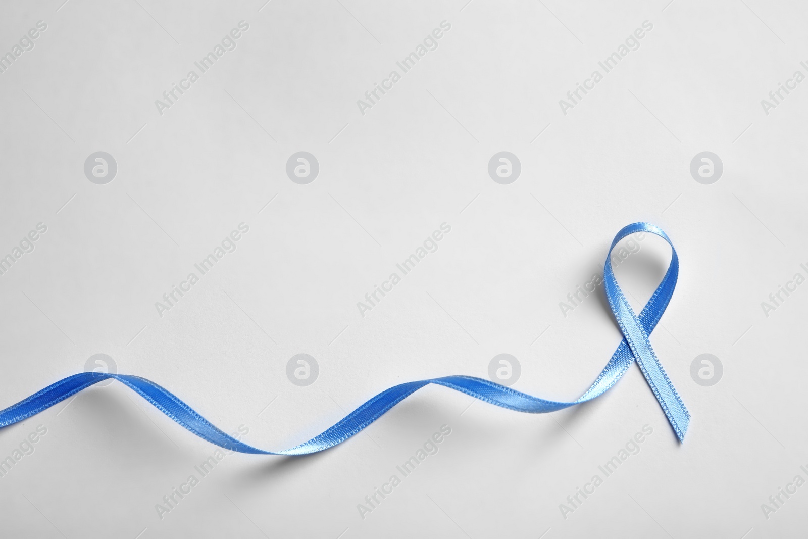 Photo of Blue ribbon on white background, top view. Cancer awareness