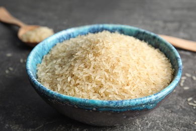 Photo of Bowl with uncooked rice on grey table